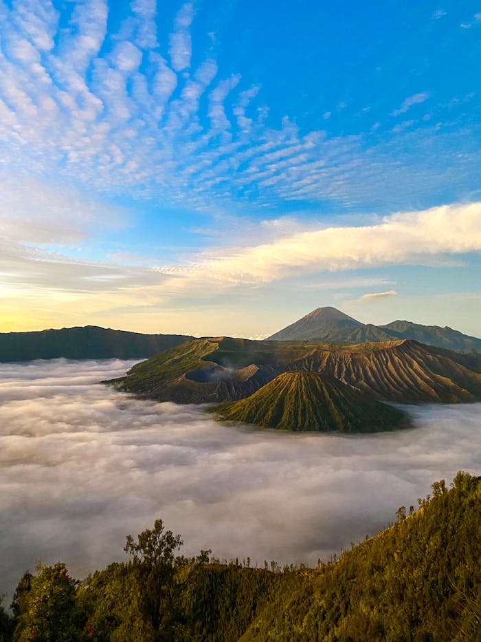 A breathtaking view of Mount Bromo in East Java, Indonesia, surrounded by misty clouds at sunrise.